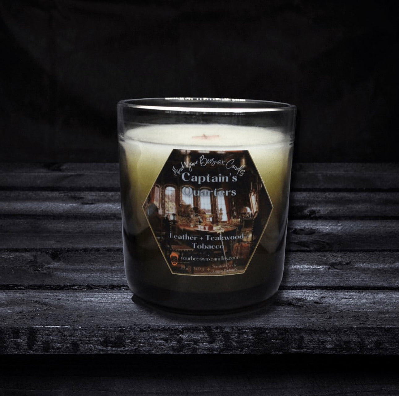 A depiction of the Captain's Quarters Luxury Beeswax Candle. The candle is elegantly presented, with a label showcasing the scent name. Its flickering flame casts a cozy glow, reminiscent of a maritime ambiance.