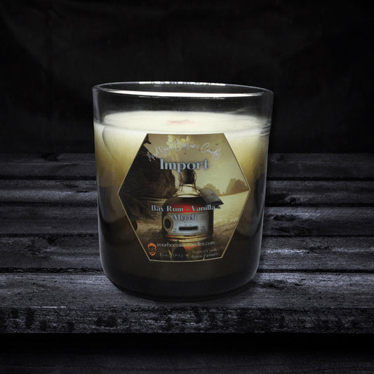 An Import Luxury Beeswax Candle showcased elegantly. The candle is adorned with a label featuring the scent name 'Import,' and its inviting glow adds an aura of intrigue and sophistication.